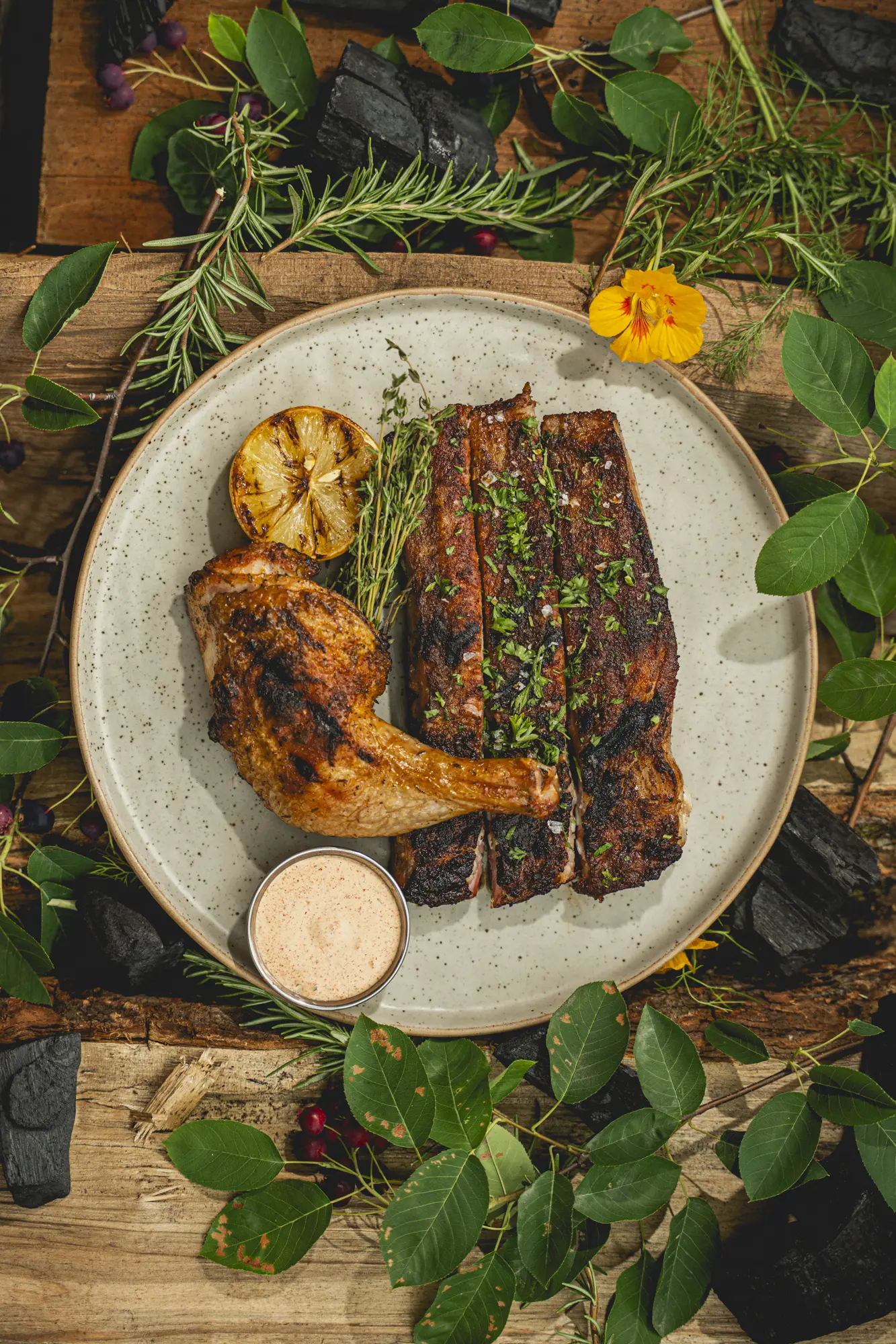 Smoked ribs and chicken arranged with herbs and grilled lemon