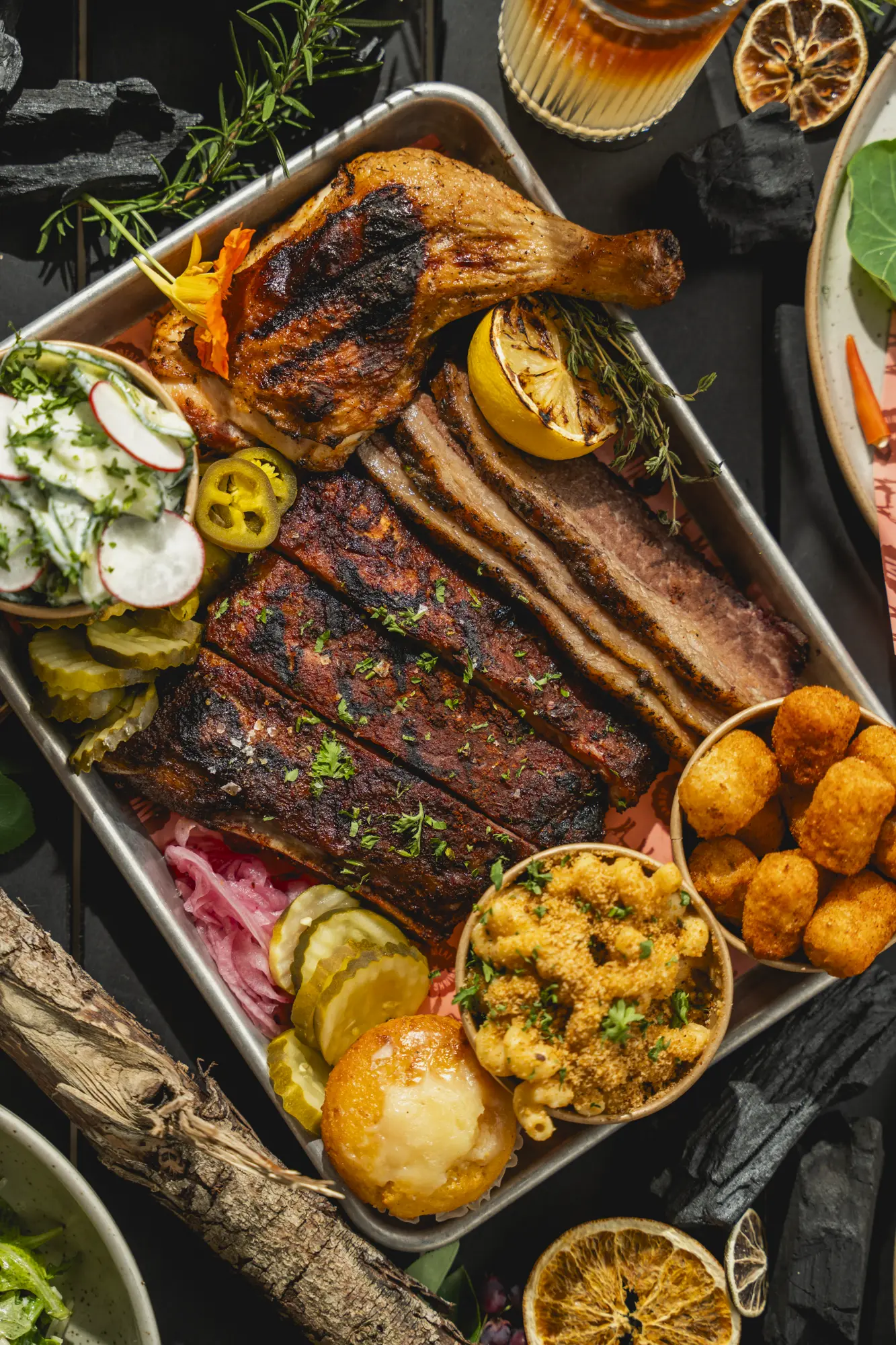 A smokehouse tray with ribs, brisket, chicken, pickles, and sides